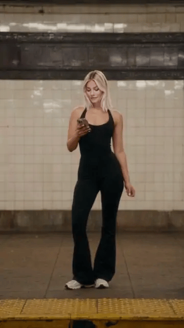 Después de que pasa el tren, el outfit cambia de un mono negro a un cuello alto con minifalda plisada